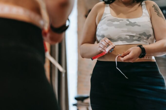 ¿Por qué engordamos en pandemia? woman measuring waist with tape in gym
