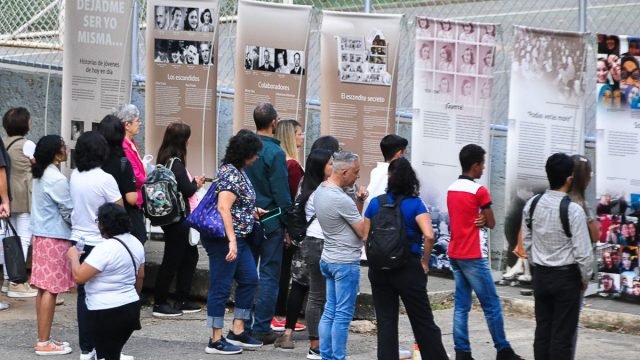 Jóvenes observa exposición In memoriam 2023